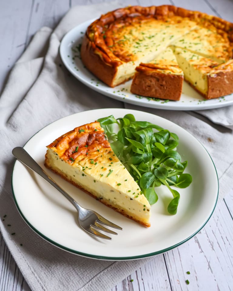 Ein Stück des pikanten Käsekuchens auf einem Teller mit etwas Salat